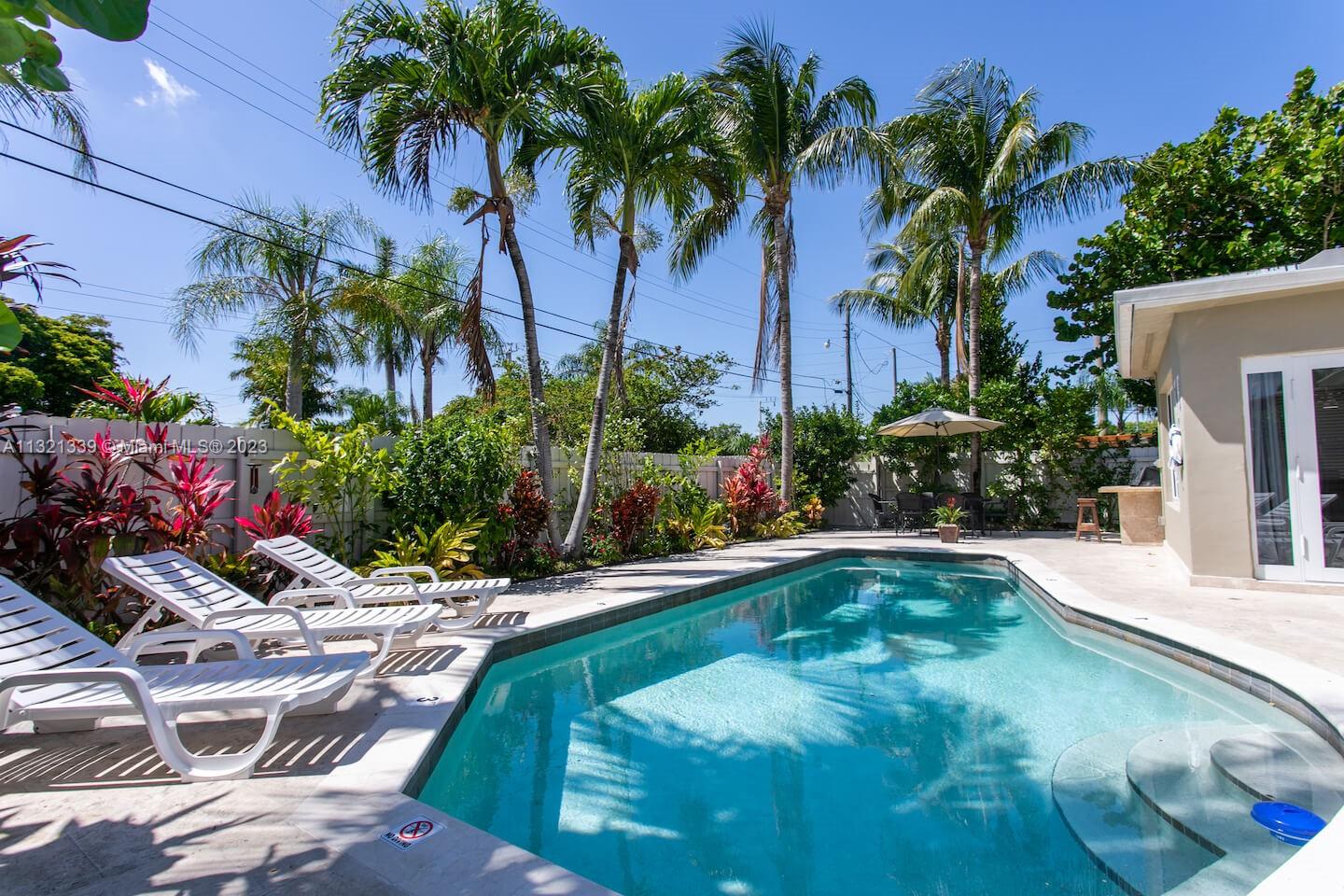 A backyard swimming pool features lounge chairs on a patio surrounded by palm trees — 1120 N 13th Terrace, Hollywood FL 33019, HOLLYWOOD, FL