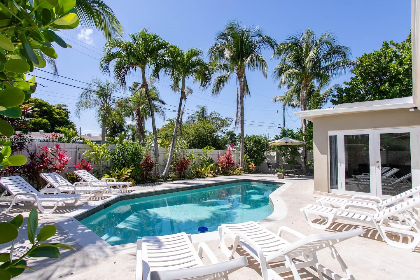 A swimming pool sits on a patio surrounded by lounge chairs, palm trees, and landscaping — 1120 N 13th Terrace, Hollywood FL 33019, HOLLYWOOD, FL