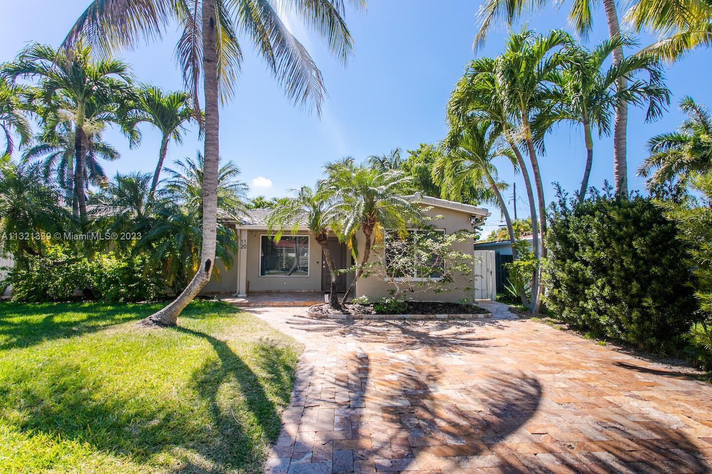A single-story house with a paved driveway and palm trees under a clear blue sky — 1120 N 13th Terrace, Hollywood FL 33019, HOLLYWOOD, FL
