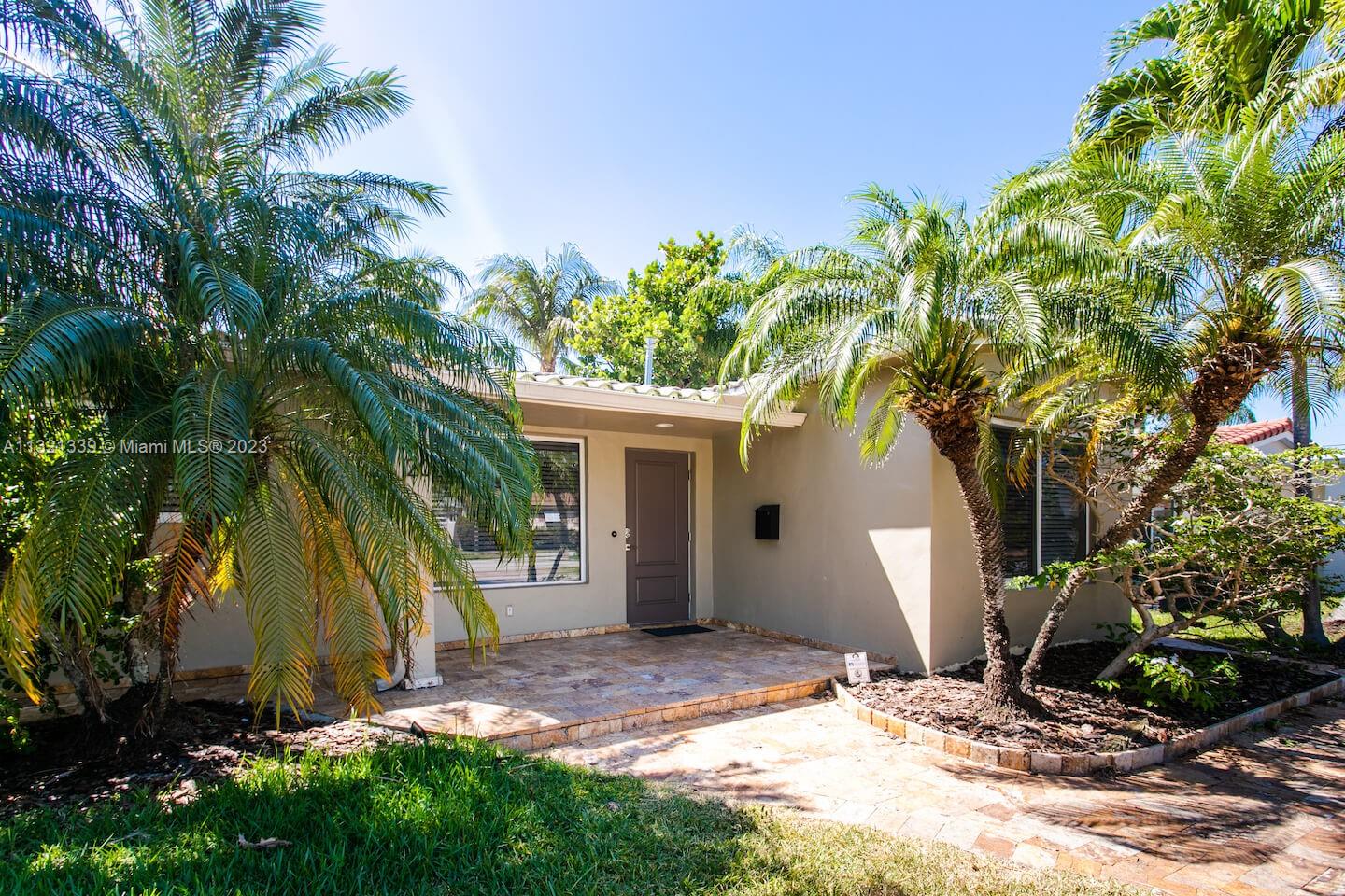 A single-story house exterior features a stone-tiled porch, a brown front door, and palm trees — 1120 N 13th Terrace, Hollywood FL 33019, HOLLYWOOD, FL