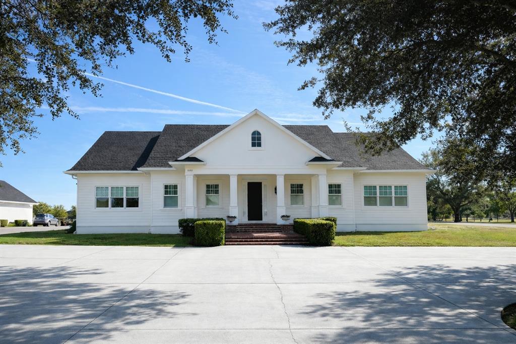 A white, single-story house with a dark roof and a large concrete driveway — 12201 CAISSON LANE, FORT MYERS, FL