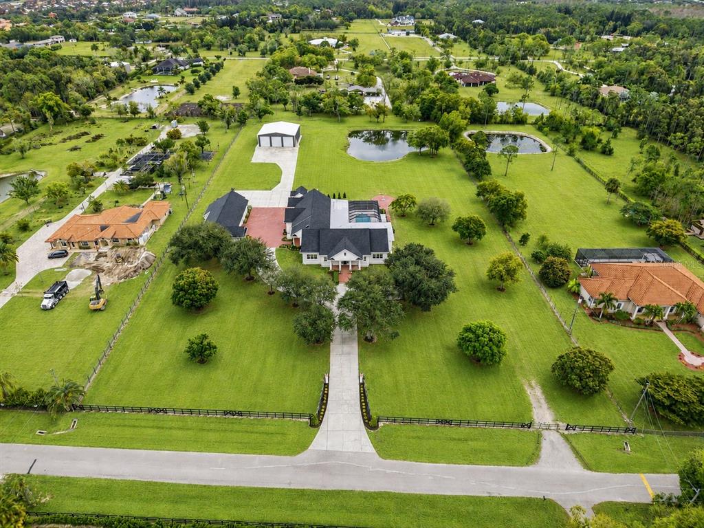 An aerial view shows a large house with a pool, driveway, and surrounding green acreage — 12201 CAISSON LANE, FORT MYERS, FL
