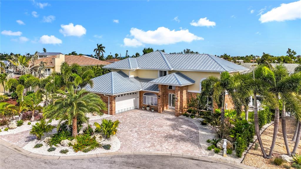 A two-story house with a metal roof and a paved driveway surrounded by palm trees — 620 NORTH POINT DRIVE, HOLMES BEACH, FL