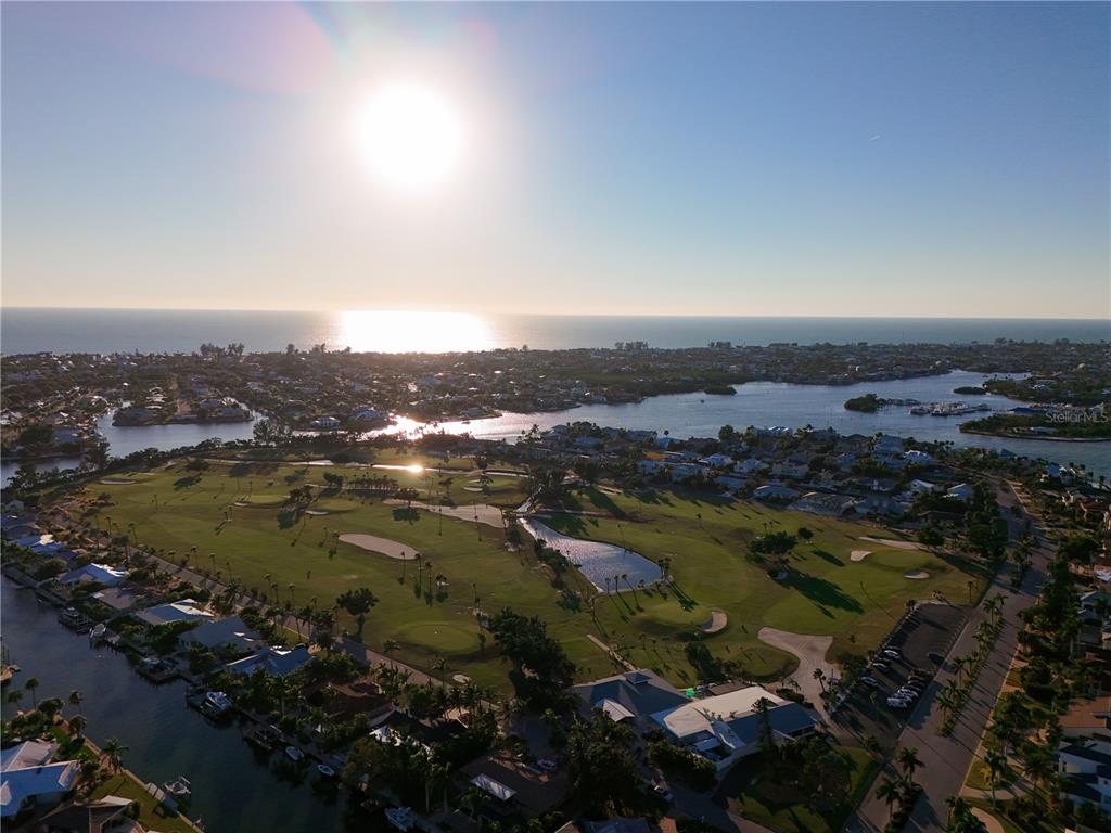 An aerial view shows a golf course surrounded by residential homes and a coastal waterway — 620 NORTH POINT DRIVE, HOLMES BEACH, FL