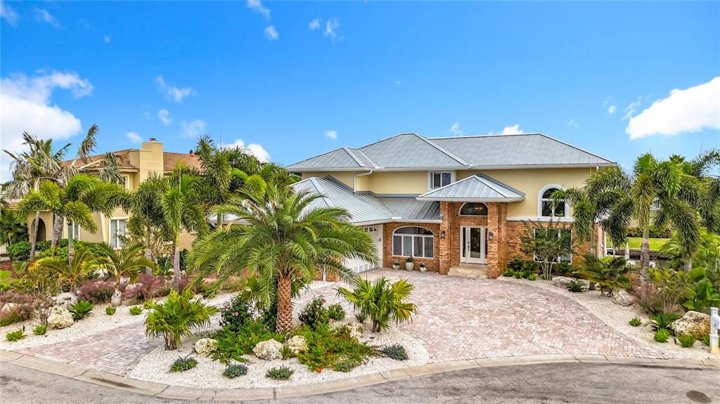 A two-story house with a metal roof, brick facade, and a circular paver driveway — 620 NORTH POINT DRIVE, HOLMES BEACH, FL
