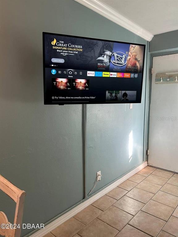 A wall-mounted television with a cord cover is displayed in a room with tiled flooring — 219 S ATLANTIC AVENUE UNIT 308, DAYTONA BEACH, FL