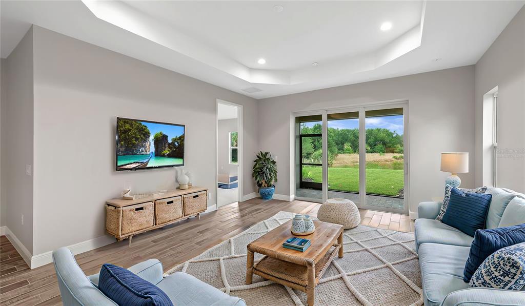 A living room features light gray walls, wood-look tile floors, a tray ceiling, and sliding doors — 2949 HERITAGE PINES DRIVE, FORT MYERS, FL