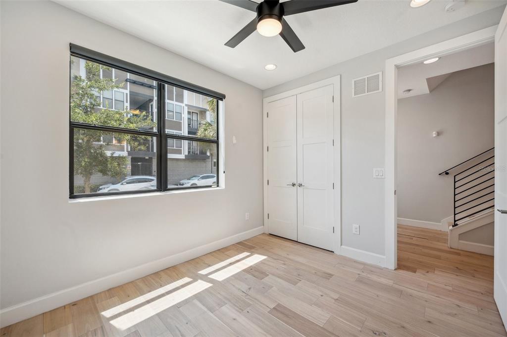 A bedroom with light wood floors, a ceiling fan, a window, and a closet door — 401 N OREGON AVENUE UNIT 9, TAMPA, FL