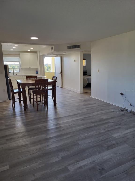 An open-concept living area features light wood-look flooring, a dining table, and a kitchen — 4650 COVE CIRCLE UNIT 611, ST PETERSBURG, FL