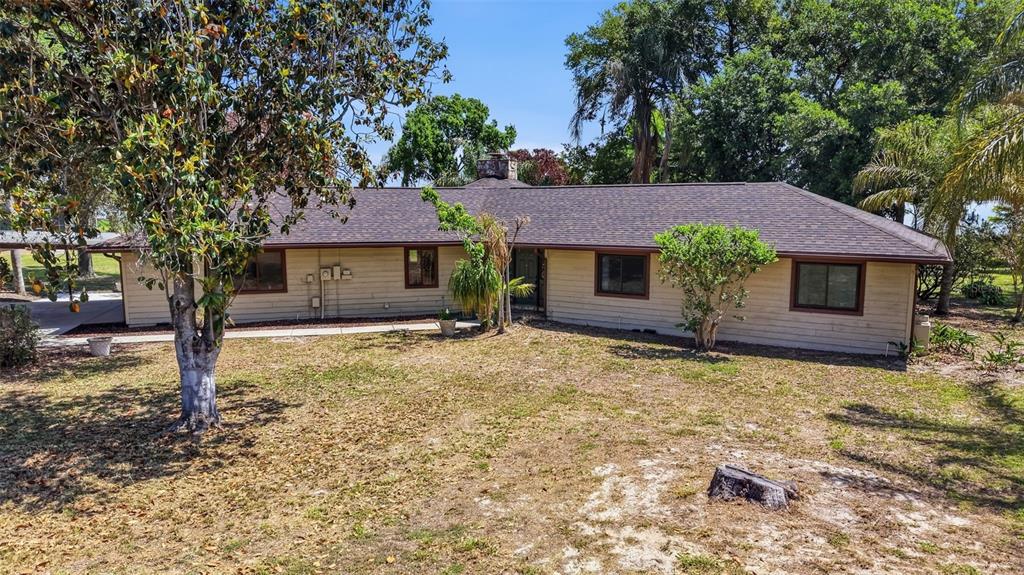 A single-story house with light-colored siding and a dark shingled roof sits on a lawn — 410 S RAMONA AVENUE, LAKE ALFRED, FL