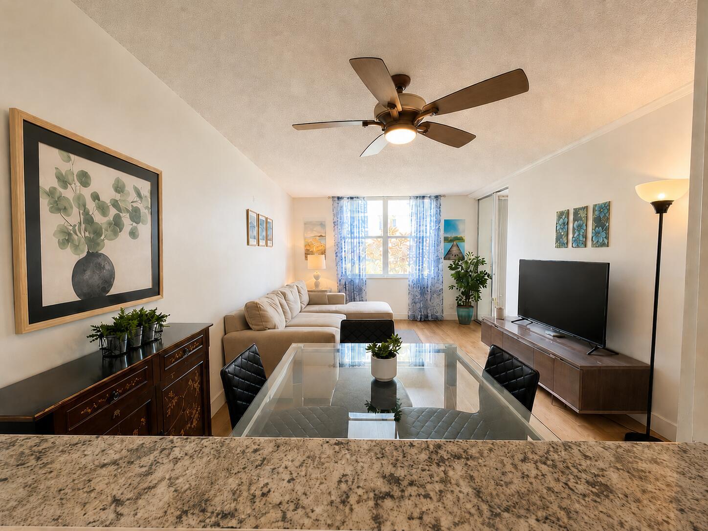 A living and dining room featuring a glass table, sectional sofa, television, and ceiling fan — 2016 S Federal Highway # 105, Boynton Beach FL 33435, BOYNTON BEACH, FL