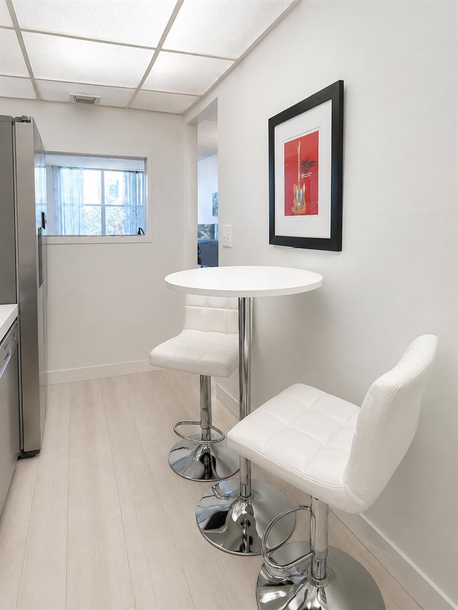 A small kitchen area features a white bistro table with two white bar stools — 2016 S Federal Highway # 105, Boynton Beach FL 33435, BOYNTON BEACH, FL