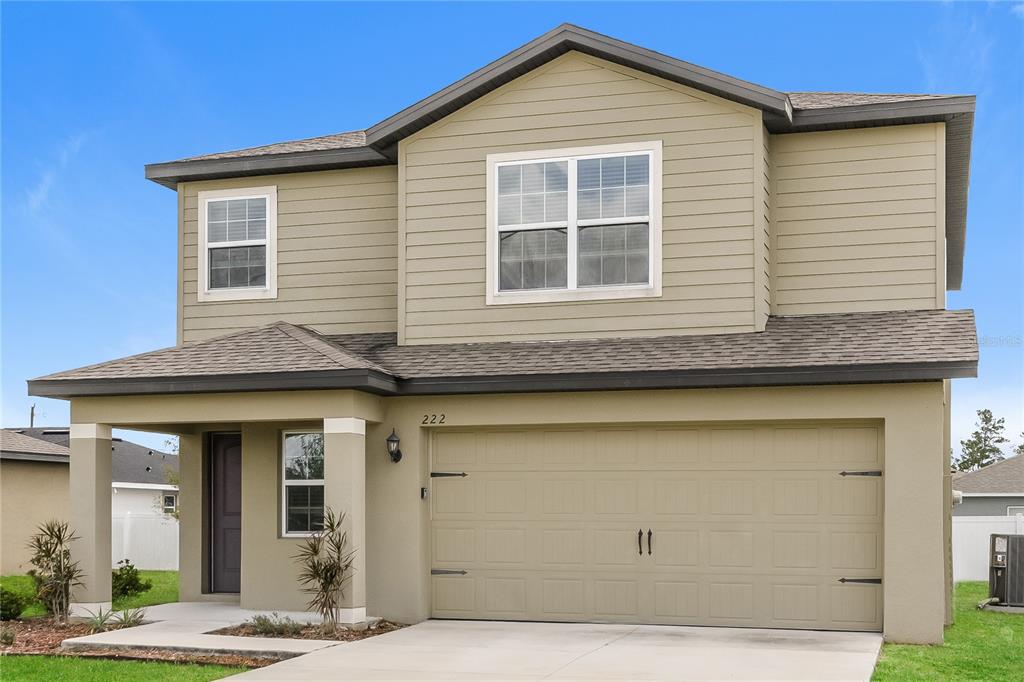 A two-story house with tan siding, a two-car garage, and a covered front entryway — 222 FIG COURT, KISSIMMEE, FL