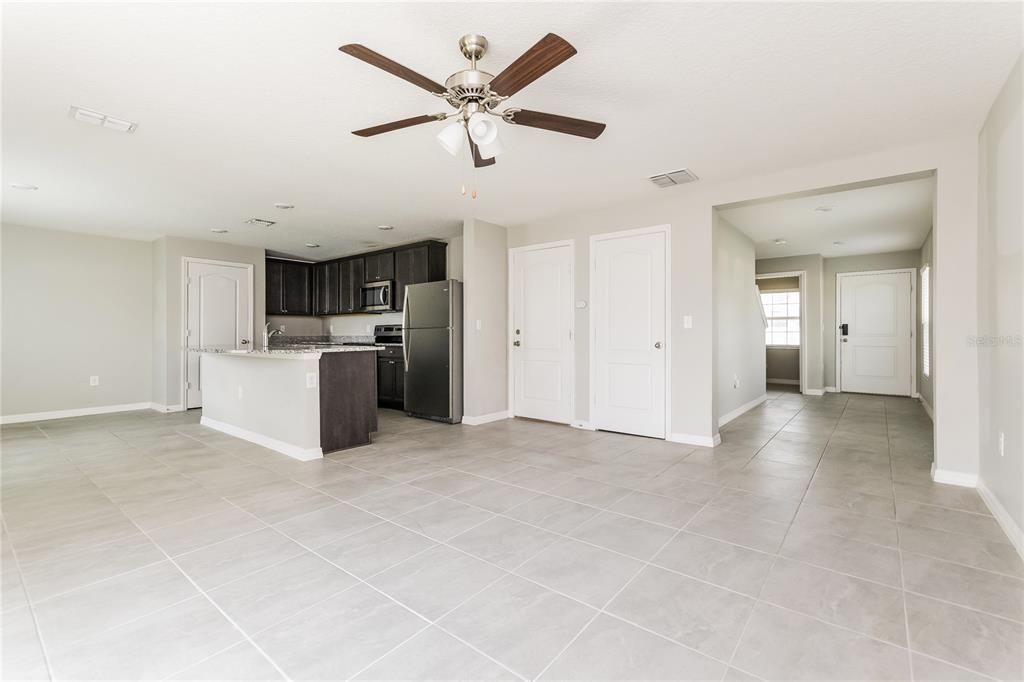 An open-concept kitchen and living area featuring tile flooring, dark cabinetry, and a ceiling fan — 222 FIG COURT, KISSIMMEE, FL