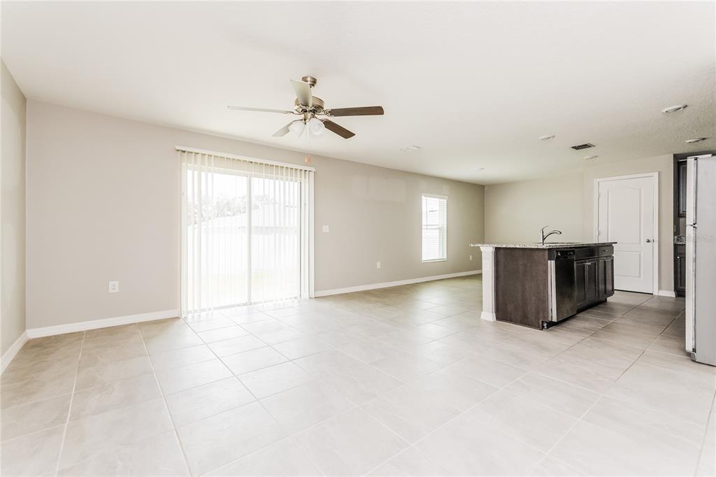 An open-concept room features light tile flooring, a ceiling fan, and a kitchen island — 222 FIG COURT, KISSIMMEE, FL