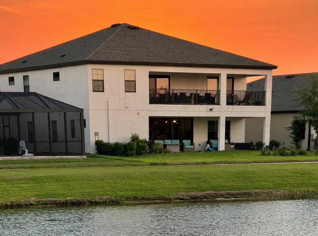 A two-story house with a balcony and a screened-in pool area overlooks a pond — 12870 TWIN BRIDGES DRIVE, RIVERVIEW, FL