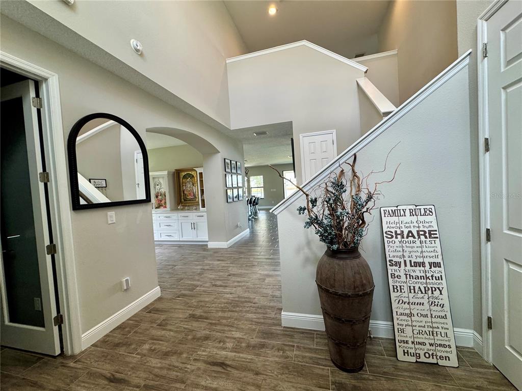 A foyer with wood-look tile flooring leads to an open living area with a staircase — 12870 TWIN BRIDGES DRIVE, RIVERVIEW, FL