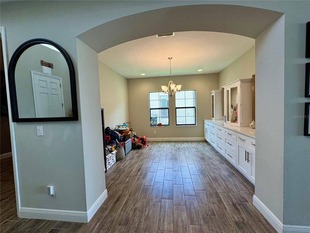 A dining room with wood-look tile flooring, a chandelier, and built-in white cabinetry — 12870 TWIN BRIDGES DRIVE, RIVERVIEW, FL
