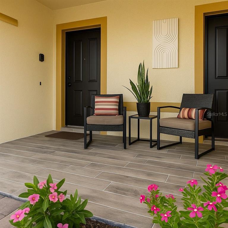 A covered patio features wood-look tile flooring, two chairs with cushions, and a small table — 438 MONROE CIRCLE, DAVENPORT, FL