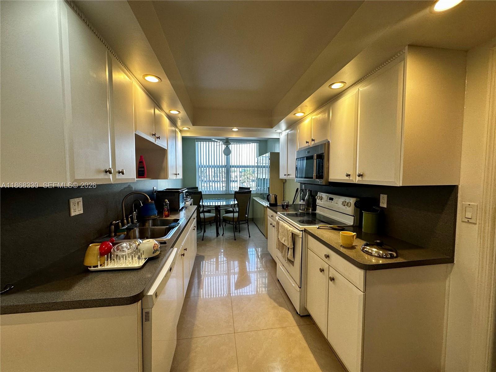 A galley-style kitchen features white cabinets, dark countertops, and a dining area with a window — 1501 S Ocean Dr # 201, Hollywood FL 33019, HOLLYWOOD, FL