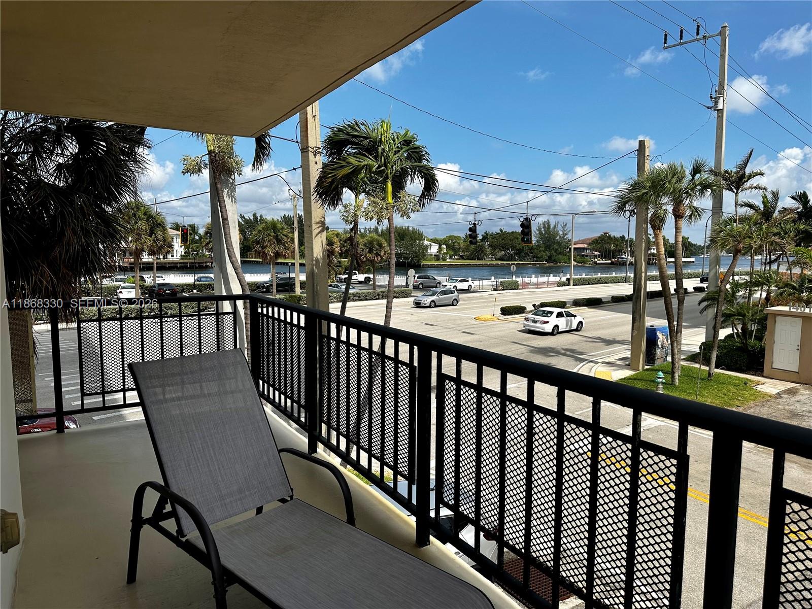 A balcony with a lounge chair overlooks a street, palm trees, and a waterway — 1501 S Ocean Dr # 201, Hollywood FL 33019, HOLLYWOOD, FL
