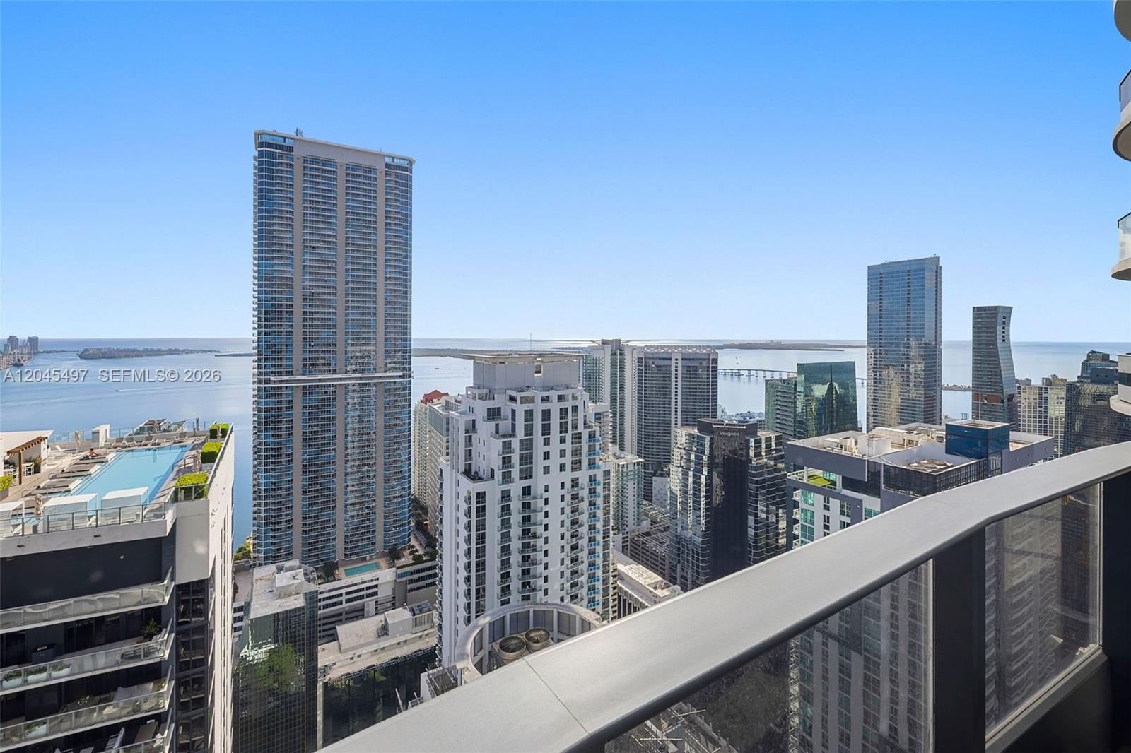 A high-angle view from a balcony overlooking a dense city skyline and the ocean — 1000 Brickell Plz, Miami FL 33131, MIAMI, FL