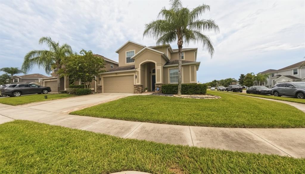 A two-story suburban house with a tan stucco exterior, a palm tree, and a driveway — 1903 HAILSHAM COURT, ORLANDO, FL