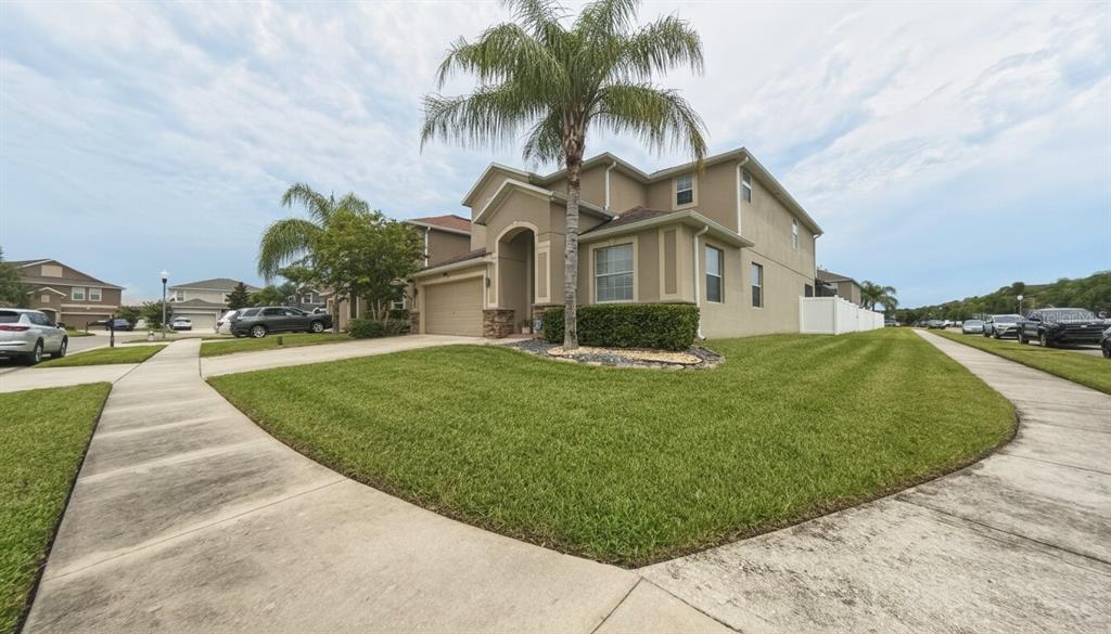 A two-story tan house with a palm tree in the front yard and a sidewalk — 1903 HAILSHAM COURT, ORLANDO, FL