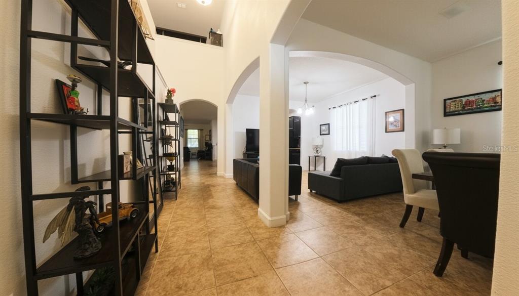 A tiled hallway leads into a living room with arched openings and high ceilings — 1903 HAILSHAM COURT, ORLANDO, FL
