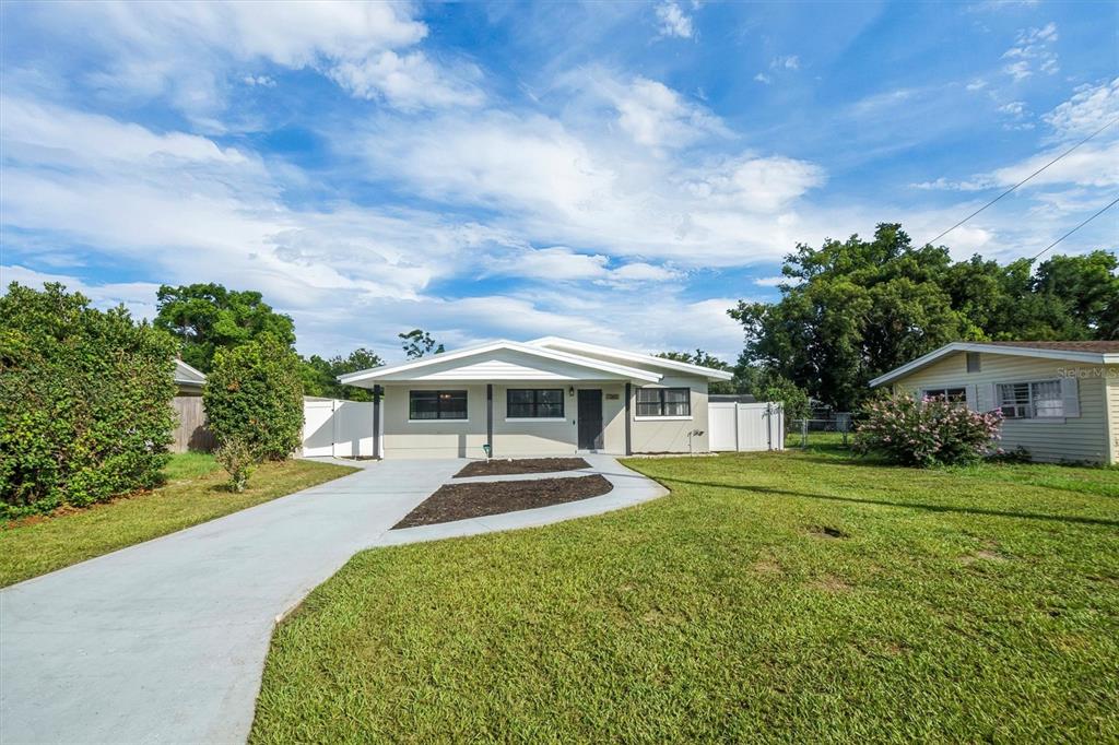 A single-story house with a light-colored exterior, a concrete driveway, and a grassy lawn — 1365 SHERIDAN STREET SW, WINTER HAVEN, FL