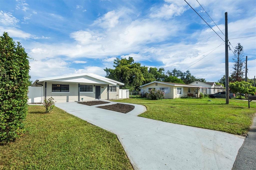 A light-colored, single-story house with a concrete driveway and a large front lawn — 1365 SHERIDAN STREET SW, WINTER HAVEN, FL