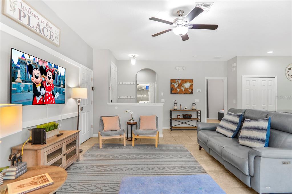 A living room features a grey sofa, two accent chairs, a television, and tile flooring — 620 LAS FUENTES DRIVE, KISSIMMEE, FL