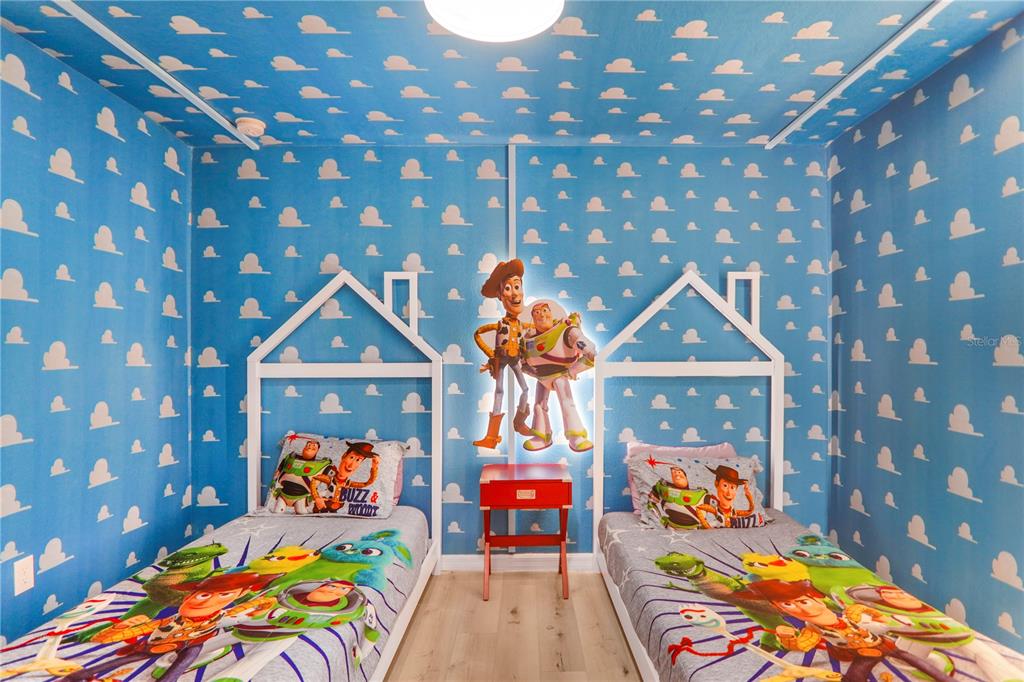 A themed bedroom features two twin beds, cloud-patterned wallpaper, and Woody and Buzz Lightyear decor — 620 LAS FUENTES DRIVE, KISSIMMEE, FL