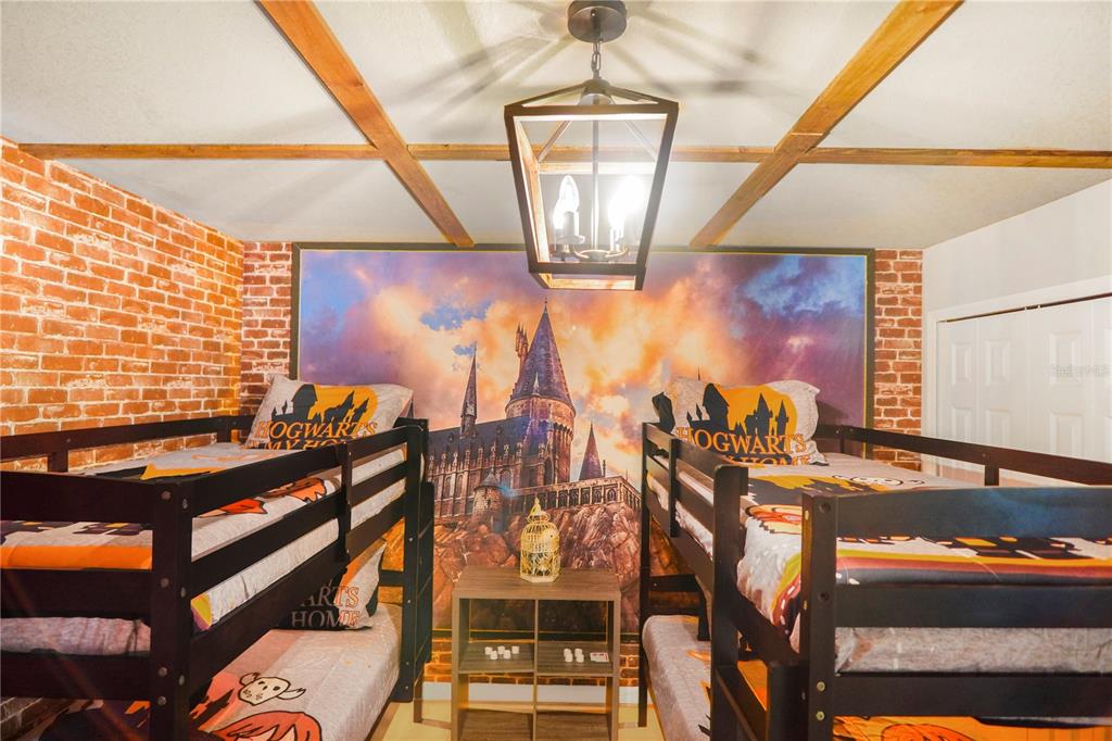 A bedroom features two bunk beds, a Hogwarts-themed wall mural, and a brick accent wall — 620 LAS FUENTES DRIVE, KISSIMMEE, FL