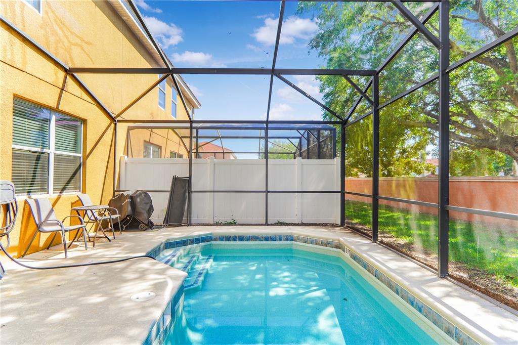 A screened-in patio features a small swimming pool and outdoor seating next to a house — 620 LAS FUENTES DRIVE, KISSIMMEE, FL