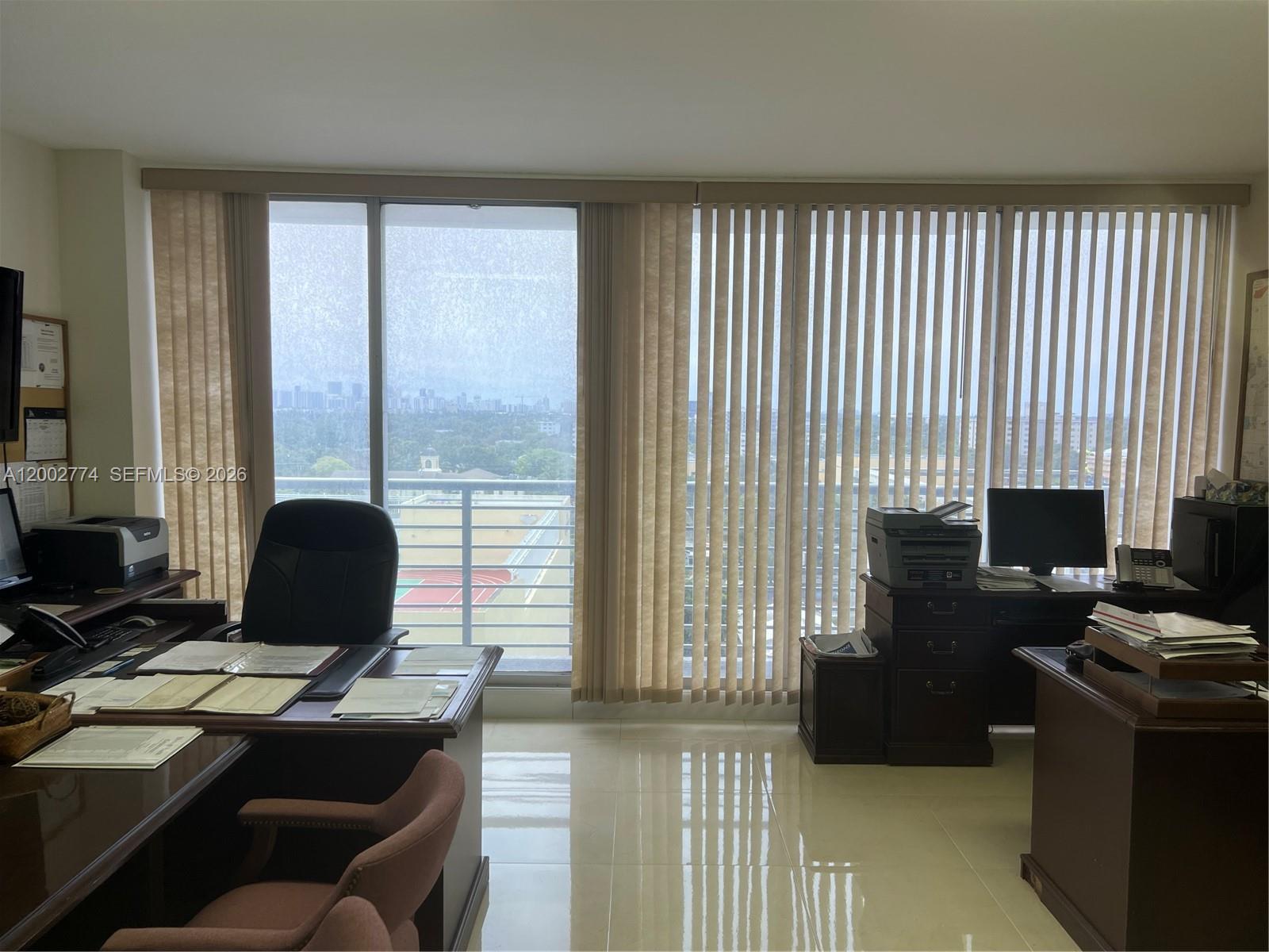 An office with two desks, tile flooring, and large windows overlooking a city skyline — 1720 Harrison St, Hollywood FL 33020, HOLLYWOOD, FL