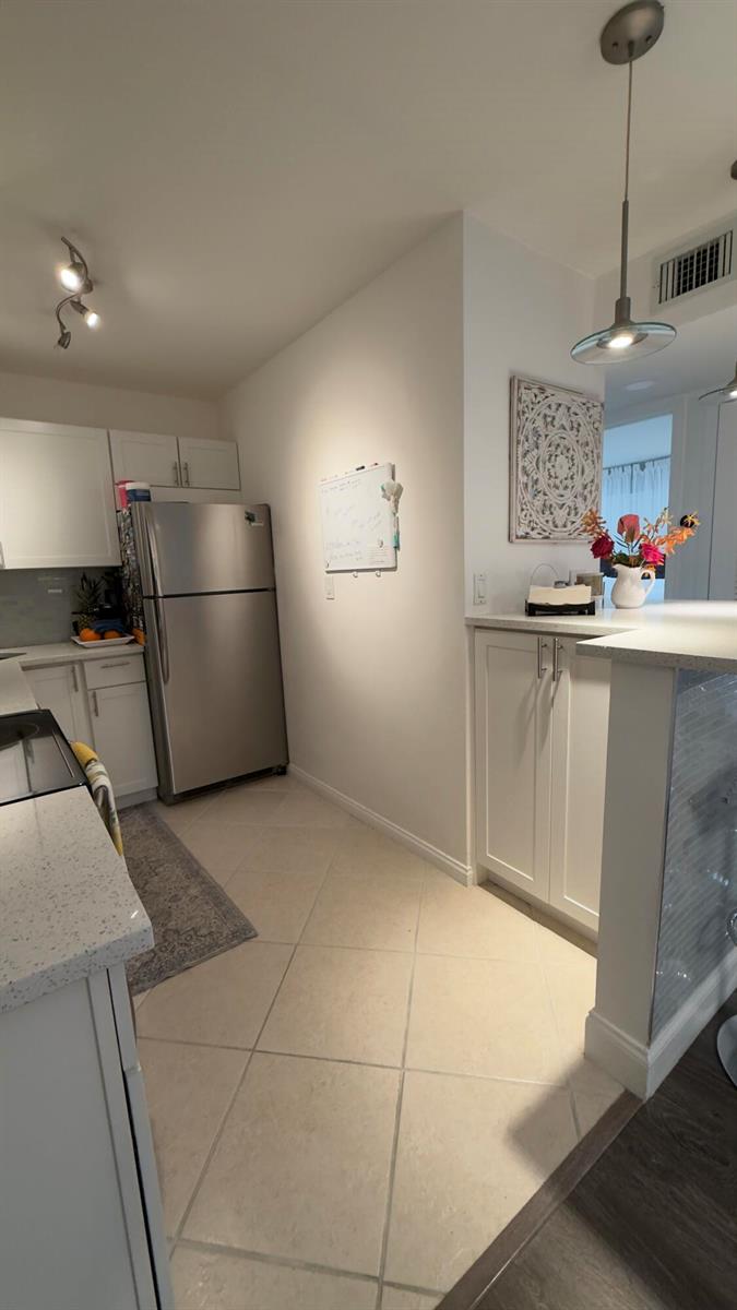 A kitchen with white cabinets, stainless steel appliances, a breakfast bar, and tile flooring — 702 SE 2nd Avenue SE # 405, Deerfield Beach FL 33441, DEERFIELD BEACH, FL