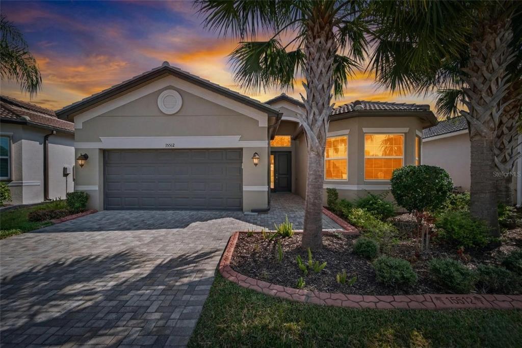 A single-story house with a paved driveway, a two-car garage, and palm trees at sunset — 15512 CORONA DEL MAR DRIVE, WIMAUMA, FL