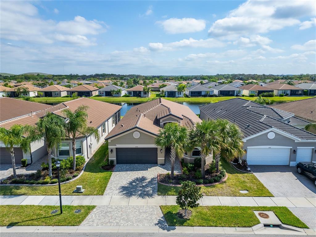 An aerial view shows a suburban house with a brown roof and palm trees — 15512 CORONA DEL MAR DRIVE, WIMAUMA, FL