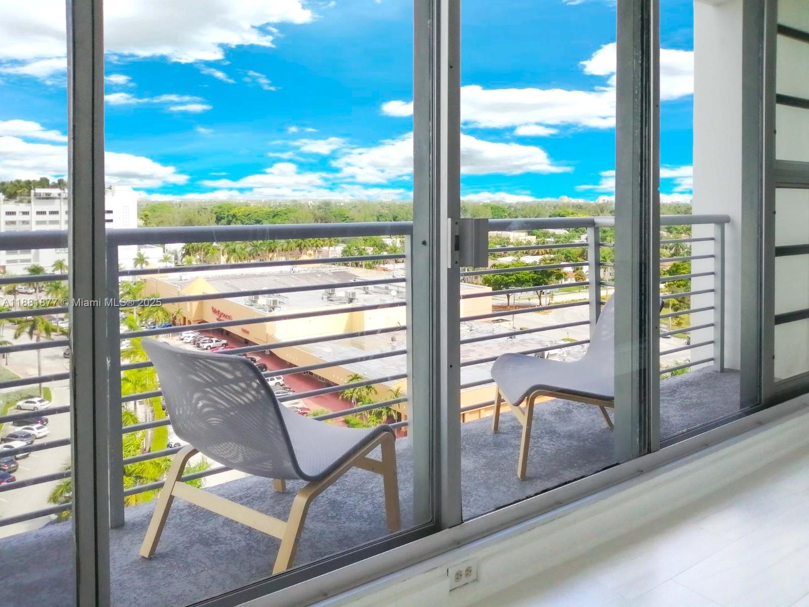 A balcony with two chairs overlooks a parking lot and a commercial building — 1720 Harrison St # 10F, Hollywood FL 33020, HOLLYWOOD, FL