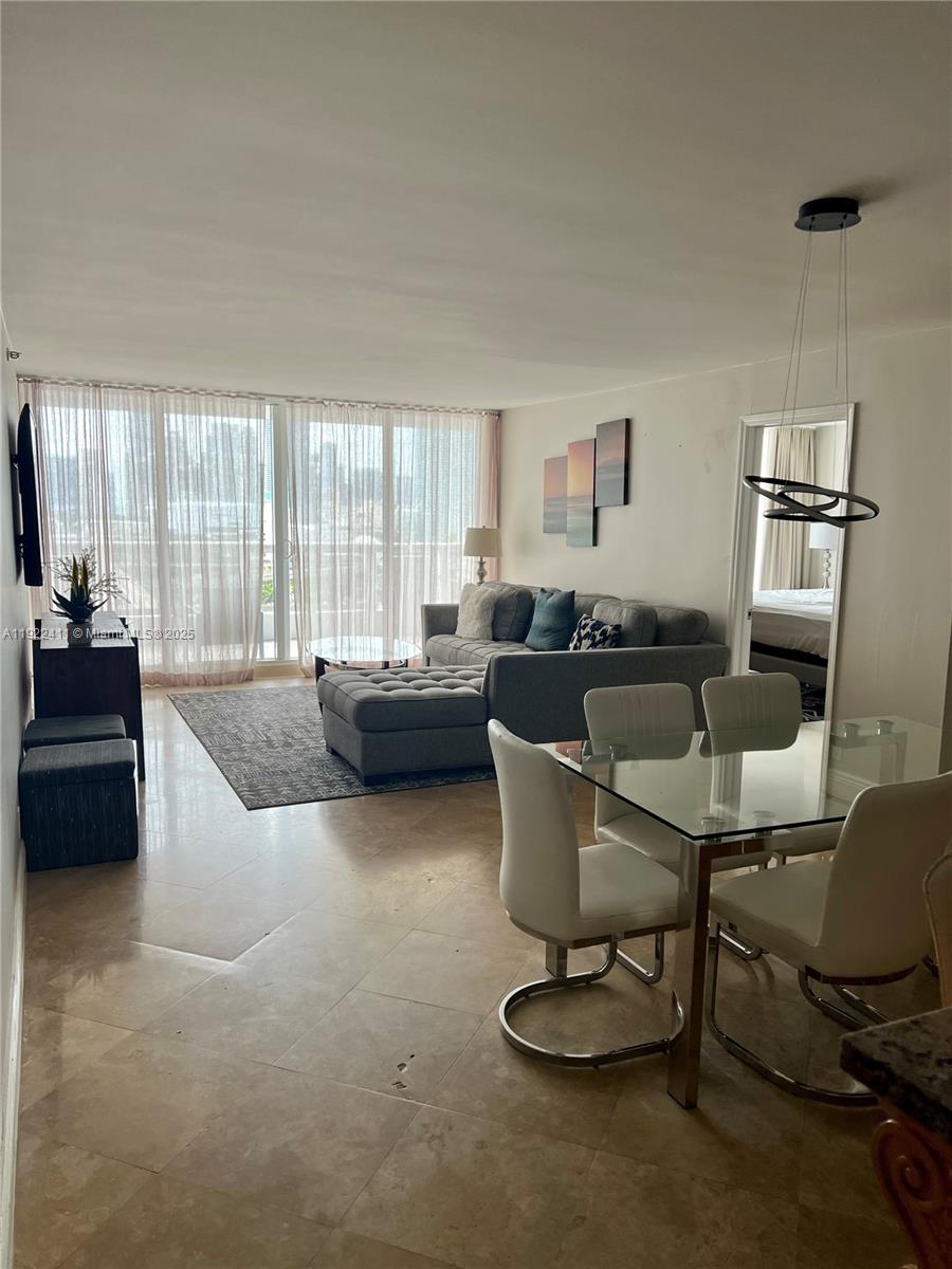 A living and dining area features tile floors, a grey sectional sofa, and glass furniture — 1717 N Bayshore Dr # 1856, Miami FL 33132, MIAMI, FL
