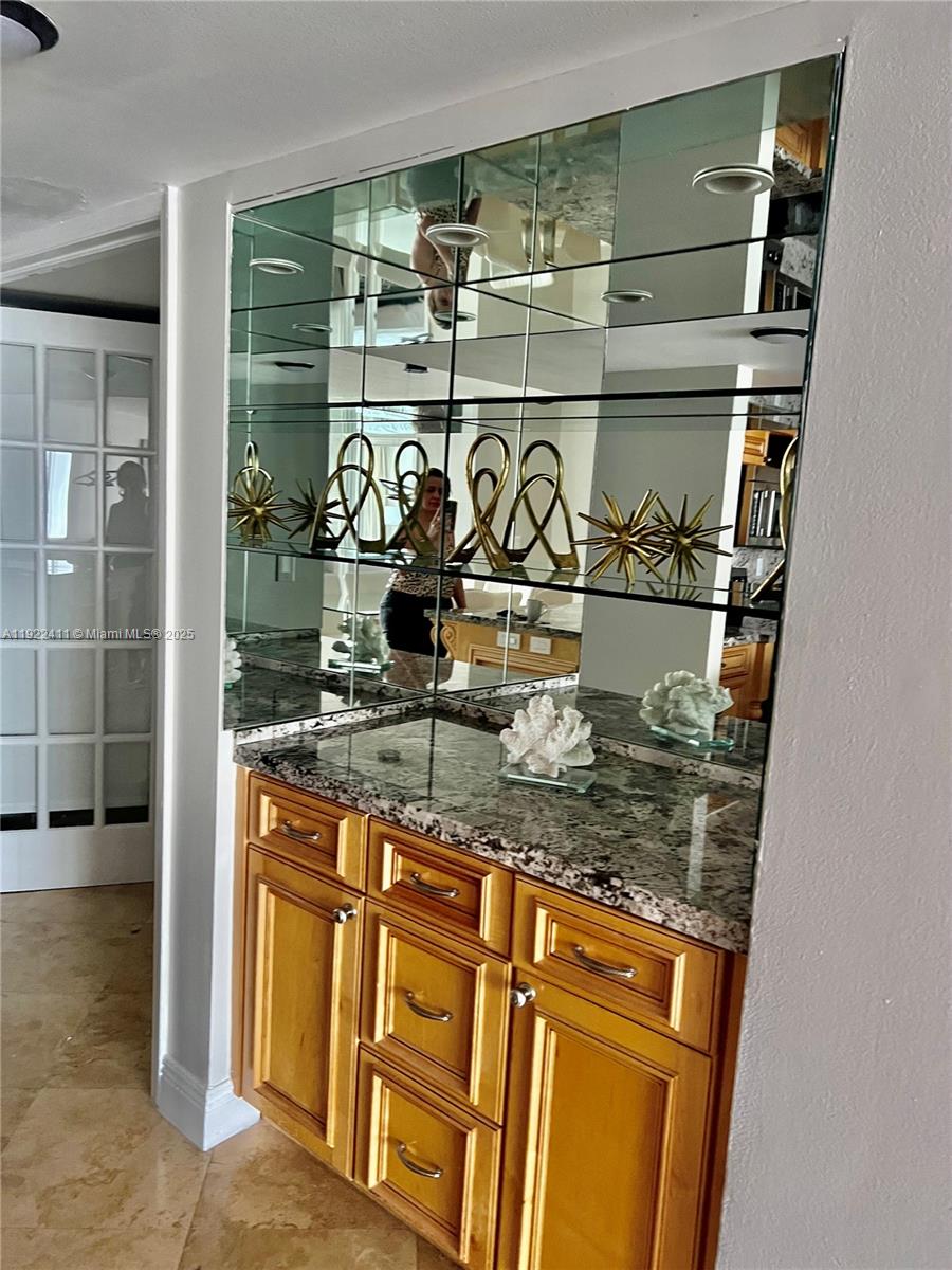 A wet bar features wood cabinets, a granite countertop, and a mirrored wall with shelves — 1717 N Bayshore Dr # 1856, Miami FL 33132, MIAMI, FL