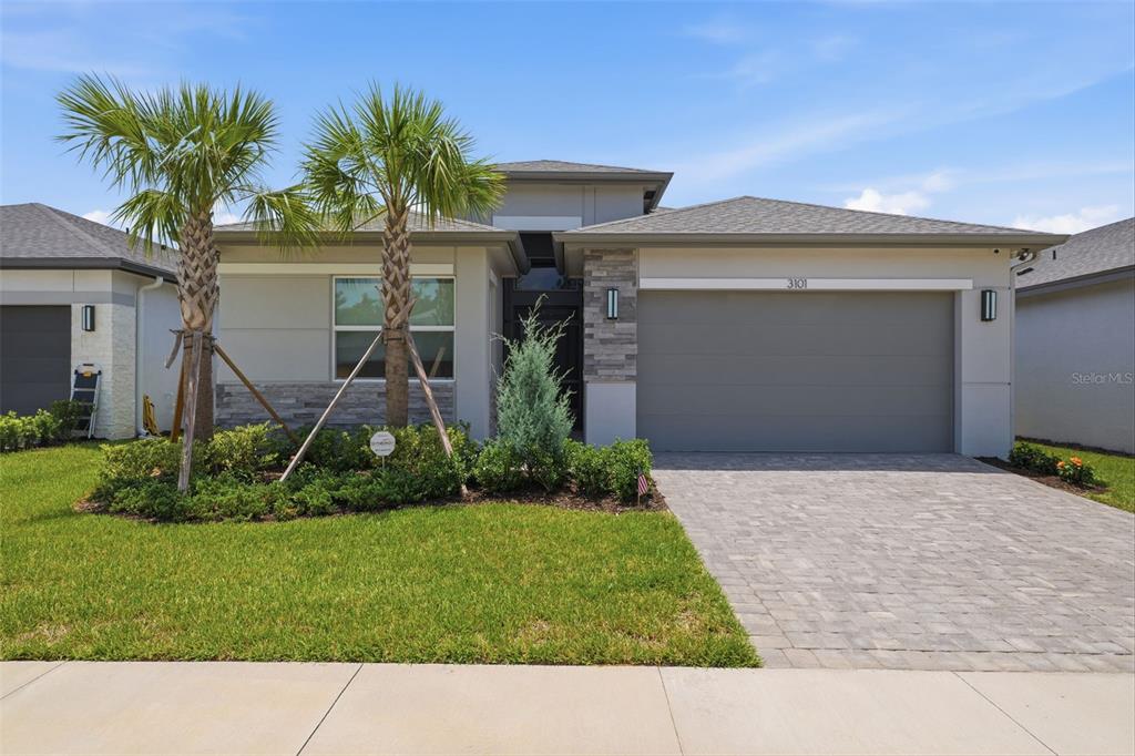 A single-story house features a gray garage, stone accents, and two palm trees in front — 3101 MALTA AVENUE, WESLEY CHAPEL, FL