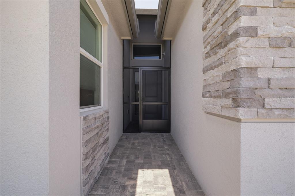A paved walkway leads to a front entrance featuring a screen door and stone accents — 3101 MALTA AVENUE, WESLEY CHAPEL, FL