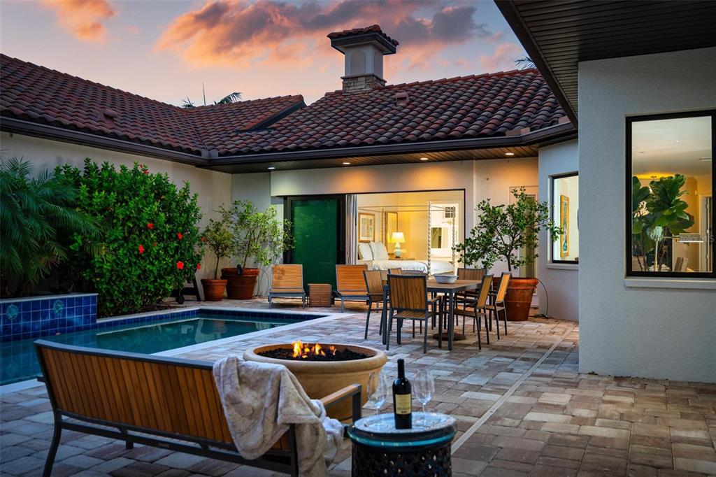 A patio with a pool, fire pit, and outdoor dining set sits beside a house — 134 E TAMPA AVENUE, VENICE, FL