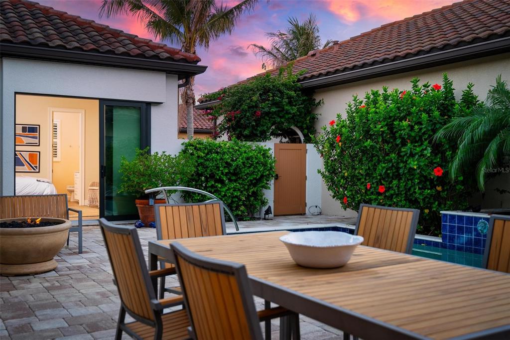 A patio with a wooden dining set, a fire pit, and a swimming pool area — 134 E TAMPA AVENUE, VENICE, FL