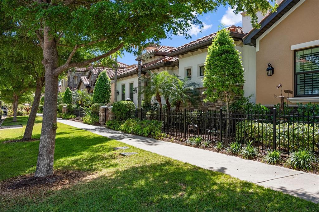 A sidewalk runs alongside a manicured lawn and a black metal fence fronting a house — 134 E TAMPA AVENUE, VENICE, FL