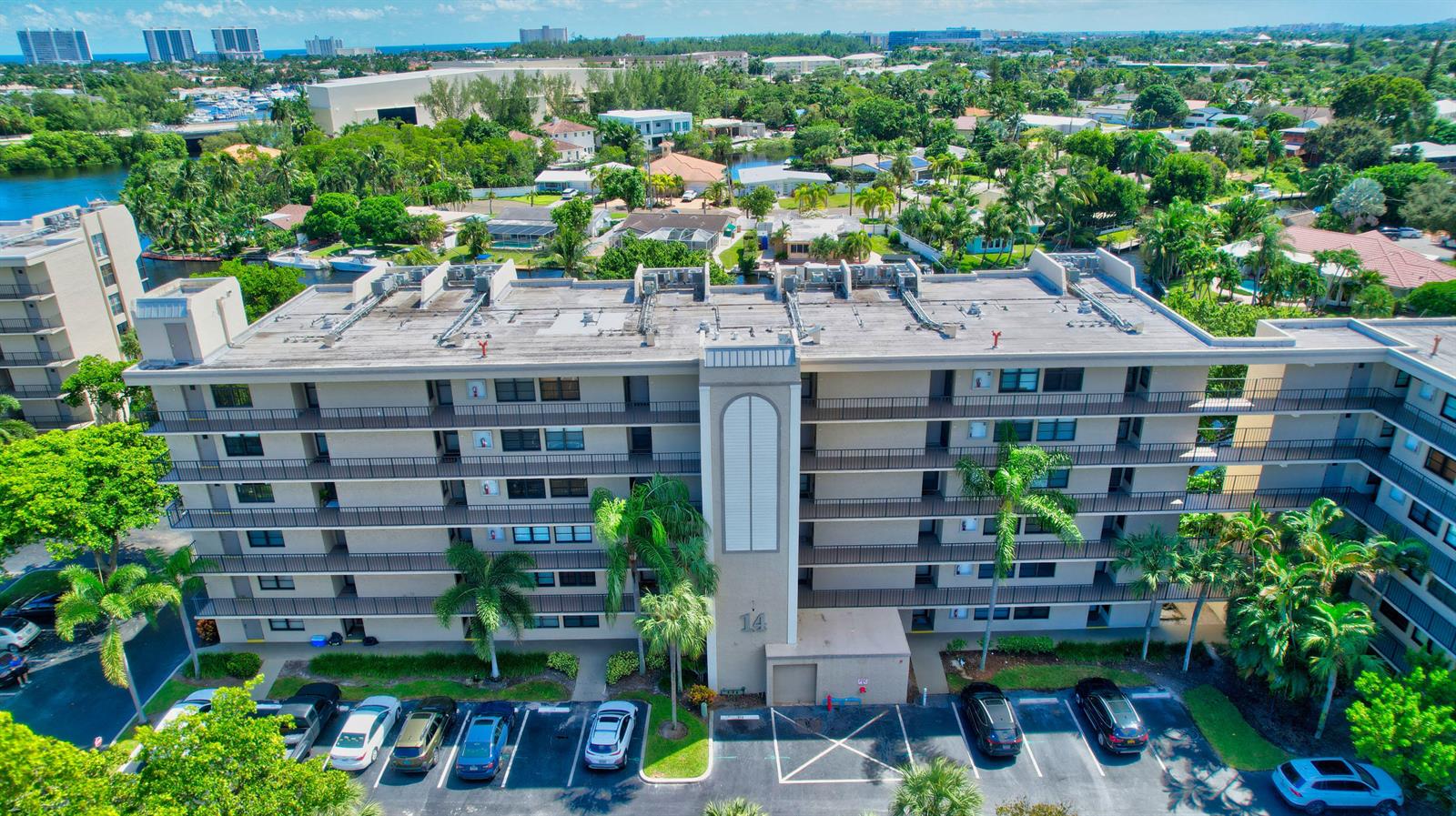 An aerial view of a multi-story apartment building with a parking lot and surrounding greenery — 14 Royal Palm Way # 2050, Boca Raton FL 33432, BOCA RATON, FL