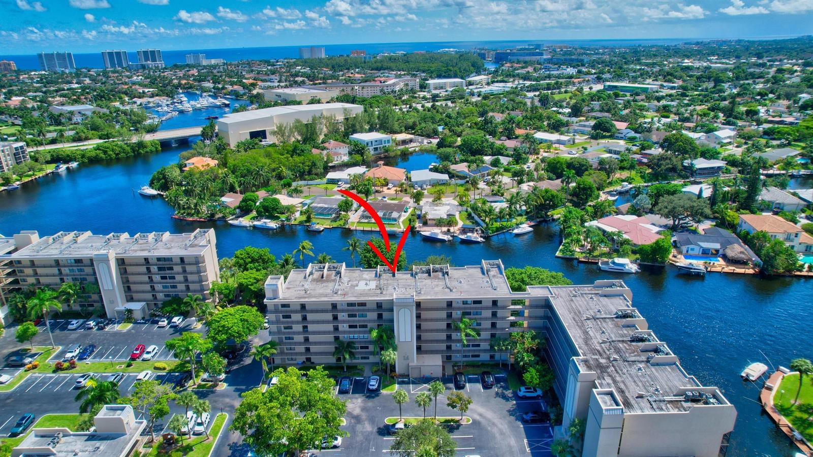 An aerial view shows a multi-story apartment building situated along a canal with boats — 14 Royal Palm Way # 2050, Boca Raton FL 33432, BOCA RATON, FL