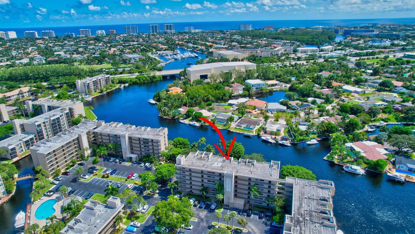 An aerial view shows a multi-story apartment building surrounded by waterways and residential neighborhoods — 14 Royal Palm Way # 2050, Boca Raton FL 33432, BOCA RATON, FL
